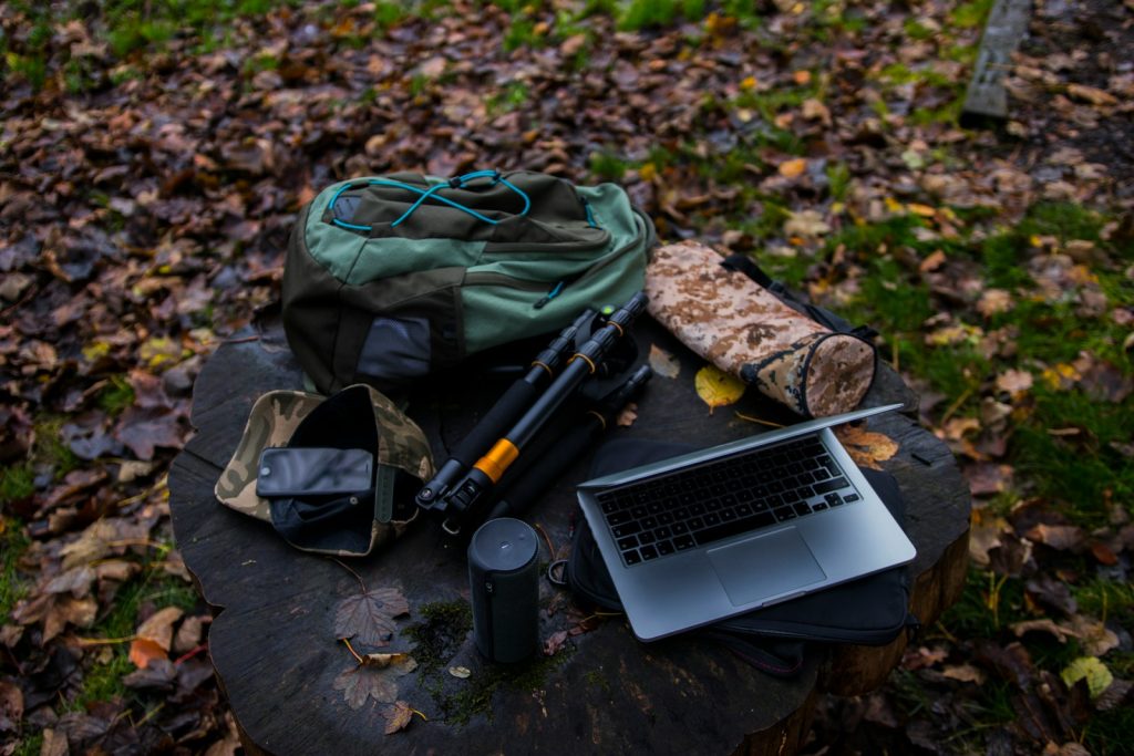 silver laptop, bag, and tripod at stump