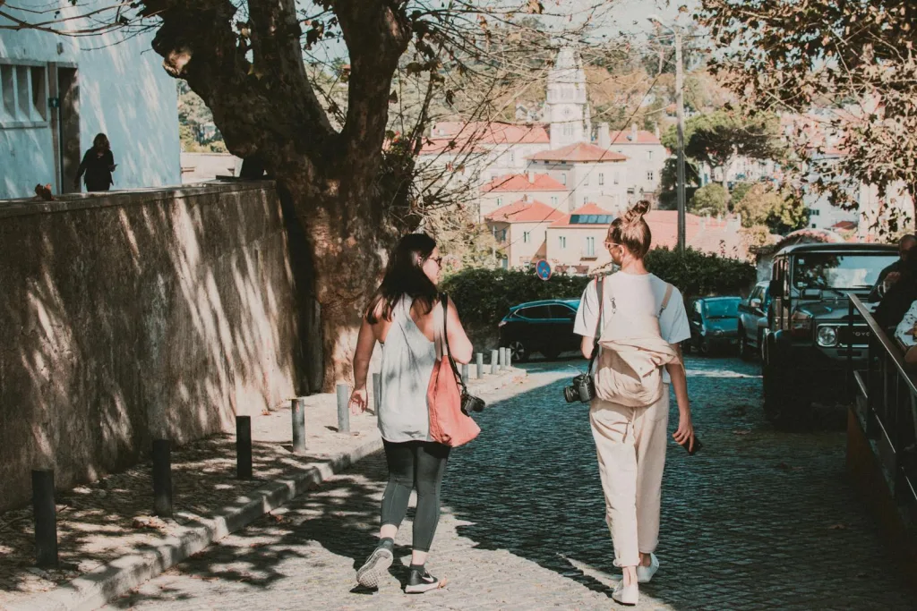 Two Women Walking by Tree