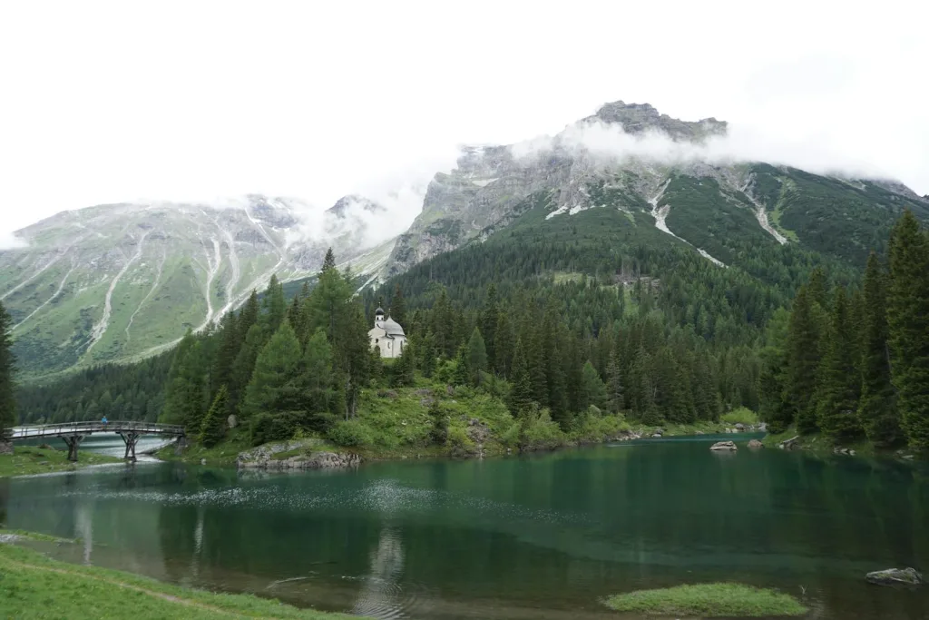 A lake with mountains in the background and a church