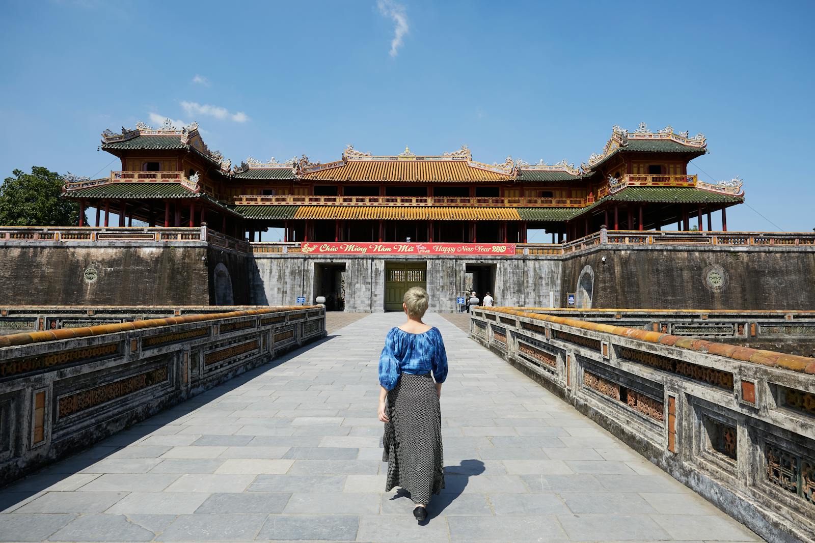 Full body back view of anonymous female traveler strolling on paved walkway near South Gate in Imperial City in Hue